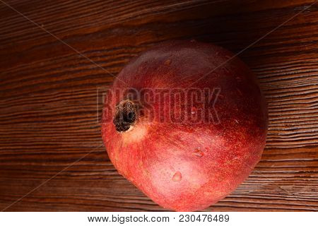 One Red Whole Juicy Pomegranate On The Wooden Background