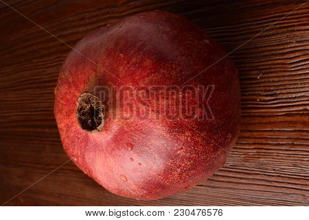One Red Whole Juicy Pomegranate On The Wooden Background