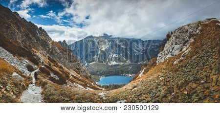 The magnificent panoramic view the crystal clear mountain Strbske Pleso lake in the picturesque valley. The mighty snow-covered Tatras in the National Park, Slovakia. Serenity of wild virgin nature.