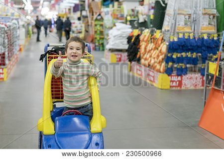 The Boy 4 Years Leaned Out Of The Children's Cart In The Building Store. Dangerous Behavior Of Child