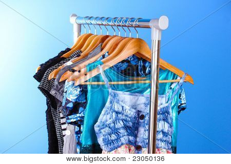 เสื้อผ้าต่าง ๆ บนไม้ hangers บนพื้นหลังสีน้ำเงิน