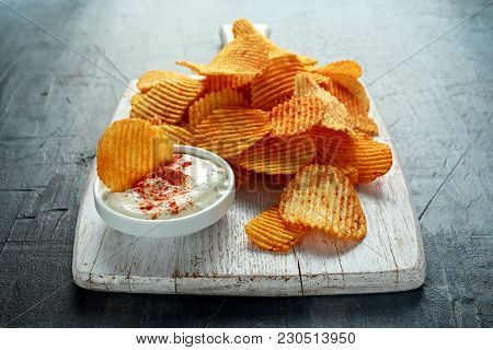 Potato Chips, Snack Crisps With Red Paprika And White Dip Sauce On White Board