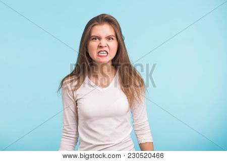 Portrait Of Young Angry Woman On Blue Background.