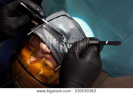 Patient In Orange Dental Glasses With A Kofferdam Is Being Treated By A Dentist