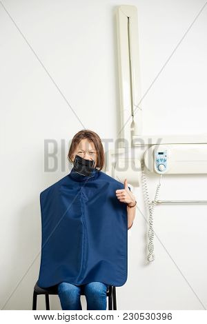 Girl Sits On The Background Of An White X-ray Machine For Teeth Using A Black Coffedram. The Girl Ha