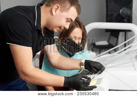 Dentist Explains Something To A Smiling Female Patient With A Rubberdam On Her Head