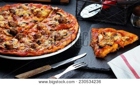Homemade Pizza With Chorizo, Mushrooms, Mozzarella And Pieces Of Chipolata Sausages On Dark Table.