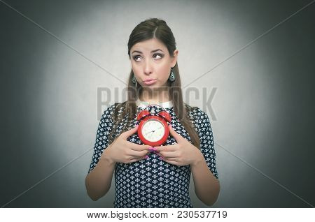 Guilty Look Woman Holding In Hands Alarm Clock And Hides Her Eyes By Looking Aside. Latecomer Studen