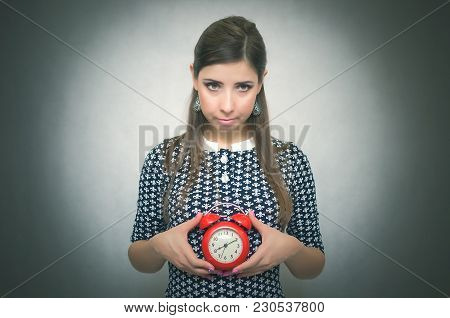 Guilty Look Woman Holding In Hands Alarm Clock And Hides Her Eyes By Looking Aside. Latecomer Studen