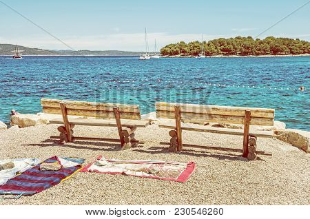 Wooden Benches And Towels On The Beach, Solta, Croatia. Summer Vacation. Sea With Yachts Scene. Yell