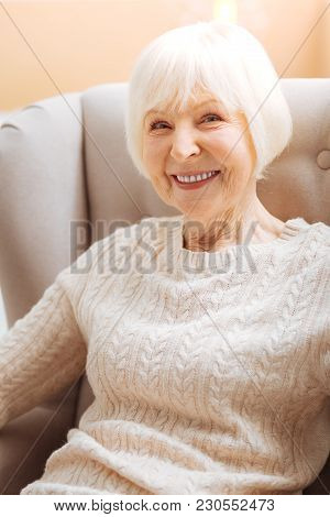 Baby Boomer. Cute Pretty Senior Woman Smiling And Feeling Happy While Sitting In A Soft Comfortable 