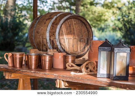 Antique Barrel, Brown Cups, Lamps And Copper Glasses On Wooden Table.