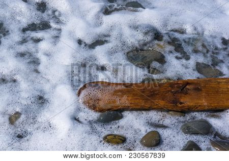 Driftwood, Washed Up By The Sea On A Pebble Beach On A Warm Summer Day