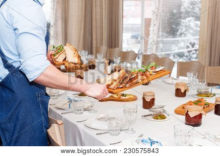 Waiter Serving Meat Dishes On Wooden Board At Restaurant, Close Up View