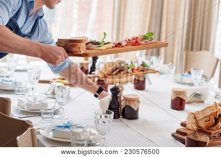 Waiter Serving Meat Dishes On Wooden Board At Restaurant, Close Up View