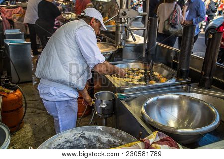Valencia, Spain - 3/11/2018: Horizontal Photo Of A Man Scooping Bunuelos Out Of Frying Oil At A Chur