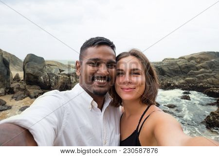 Young Caucasian Woman And Asian Man Making Selfie During Honey Moon In Sri Lanka On Beach. Concept O
