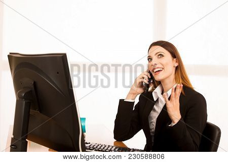 Beautiful Business Woman Talks On Smert Phone In Office At Her Desk