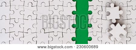 The Green Path Is Laid On The Platform Of A White Folded Jigsaw Puzzle. The Missing Elements Of The 