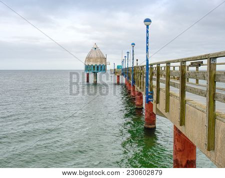 Long Wooden Pier On Baltic Coast During Morning Windless. Cold Weather, Peaceful Silent Day. Empty M