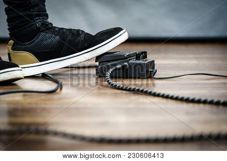 Man With Musical Instrument Setting Up Guitar Audio Stomp Box Effects And Cables In Music Studio