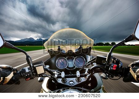 Biker on a motorcycle hurtling down the road in a lightning storm - Forggensee and Schwangau, Germany Bavaria