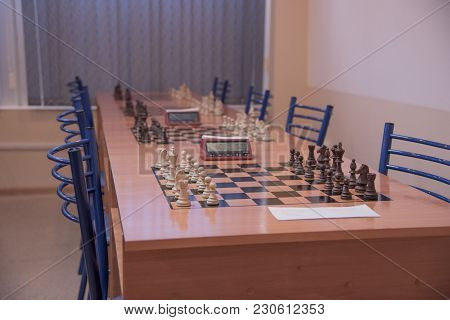 Chess Club With Long Tables. Wooden Chess Board With Wooden Chess Pieces And Chess Clock.