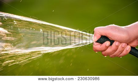 Woman Hand Holding Rubber Water Hose And Using Finger Close End Of Rubber Water Hose To Make  Water 
