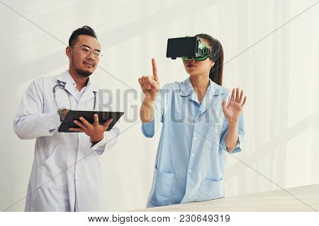 Doctors Using Application On Tablet Computer To Test Vr Goggles