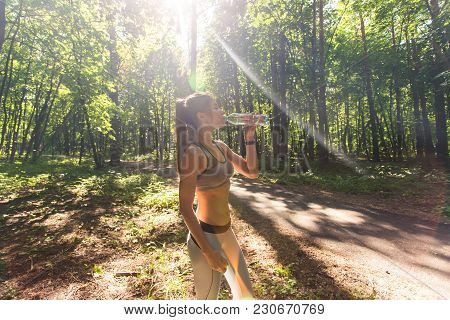 Young Woman Drinking Water After Running Outdoors.