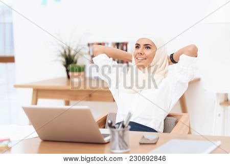 The Arab Woman In The Hijab Relaxes. She Is Sitting At The Desk In The Office. She Has A Little Brea