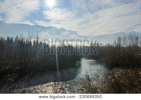Tree-filled River Banks Near The Town Of Echelles, In The French Savoy Eary, On A Dramatically Cloud