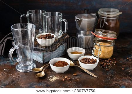 Coffee In Glass Cup, Coffee Beans, Ground Coffee And Brown Cane Sugar On Dark Background