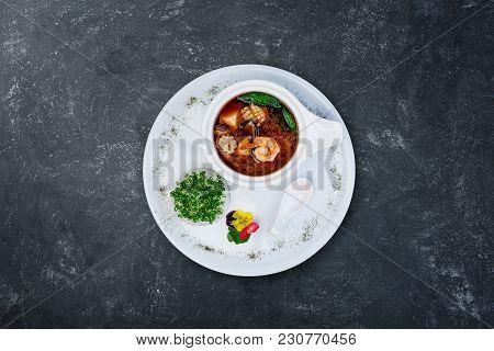 Miso Soup With Prawns In A White Ceramic Bowl, Served On The White Plate And Grey Plastered Backgrou