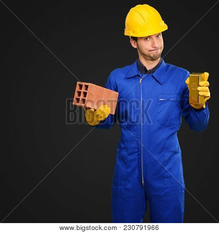 Engineer Holding Brick And Goldbar On Black Background