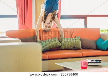 A Woman Is Standing On His Hands Upside Down In The Living Room.