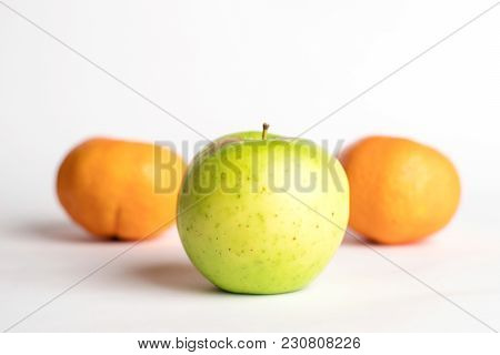 One Green Juicy Apple On Centre With Small Spots With 2 Mandarins Below On A White Background With A