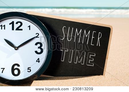 closeup of a clock and a signboard with the text summer time written in it, on the sand of a beach