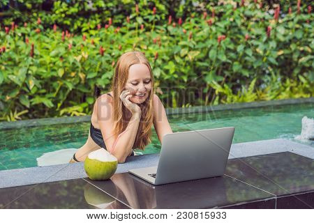 Young Female Freelancer Sitting Near The Pool With Her Laptop In The Hotel Browsing In Her Smartphon