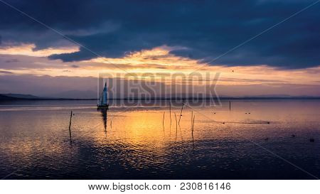 Yacht Sailing At Sunset With Cloudscape And Reflections