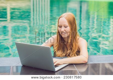 Young Female Freelancer Sitting Near The Pool With Her Laptop In The Hotel Browsing In Her Smartphon