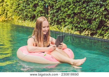 Young Female Freelancer Sitting Near The Pool With Her Laptop In The Hotel Browsing In Her Smartphon