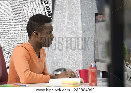 Young Black Man In The Office Behind His Desk.