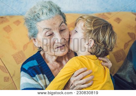 Portrait Of A Happy Boy Kissing Happy Grandmother At Home
