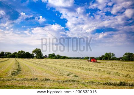 English rural landscape with  tractor collecting cut hay making silage bales Southern England UK