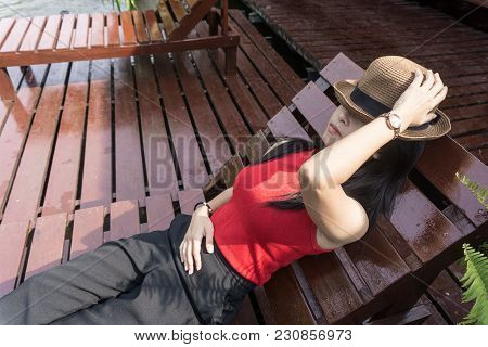 Asian Girl In The Resort In Red Clothes And Hat Sleep On Bed Pool., Background Of A Beautiful River.