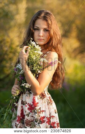 The Young Beautiful Girl, With A Bouquet Of Flowers, Has A Rest And Enjoys Beauty Of The Nature In T