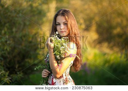 The Young Beautiful Girl, With A Bouquet Of Flowers, Has A Rest And Enjoys Beauty Of The Nature In T