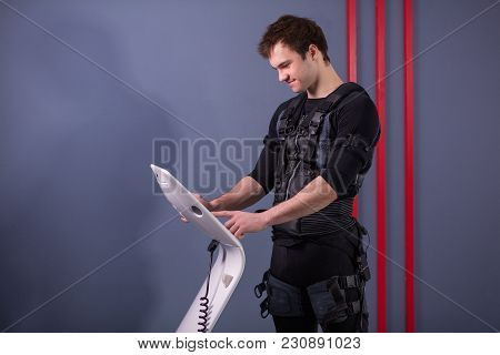 Male Athlete Select Intensity Of Ems Electro Muscular Stimulation Machine