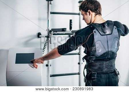 Male Athlete Pushing On Screen On Ems Machine Regulating Intensity